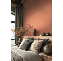 Ložnice s postelí, polštáři, vázami a dekoracemi v teplých tónech