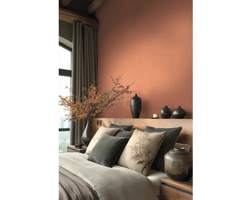 Ložnice s postelí, polštáři, vázami a dekoracemi v teplých tónech