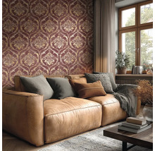 Obývací pokoj s tapetou s damaškovým vzorem v tmavě červené a zlaté barvě, hnědou koženou pohovkou s polštáři a oknem.