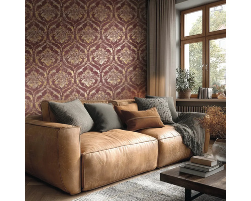 Obývací pokoj s tapetou s damaškovým vzorem v tmavě červené a zlaté barvě, hnědou koženou pohovkou s polštáři a oknem.