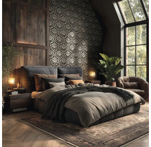 Tmavá ložnice s tapetou s ornamenty, dřevěným obložením stěn, čalouněnou postelí, koženým křeslem a kobercem v rustikálním stylu.