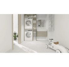 Světlá prádelna s pračkou, sušičkou a koupelnovým nábytkem.