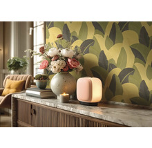 Dekorativní obytné prostředí se stolní lampou, květinami, svíčkou a vzorovanou tapetou.