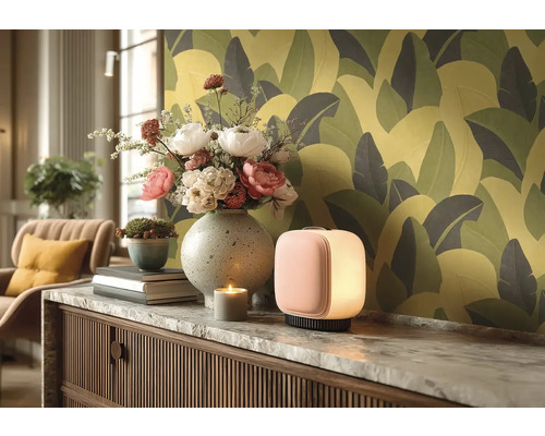 Dekorativní obytné prostředí se stolní lampou, květinami, svíčkou a vzorovanou tapetou.