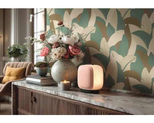 Moderní pokoj s tapetou s velkými listy. Na komodě s mramorovou deskou stojí stolní lampa, váza s květinami a dekorace.