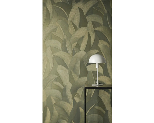 Vliesová tapeta se strukturovaným vzorem tropických listů. Bílá stolní lampa na černém stolku stojí před stěnou.