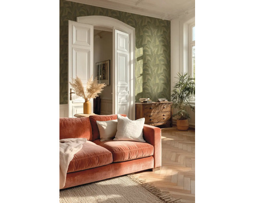 Obývací pokoj se zelenou tapetou se vzorem listů, terakotovou sametovou pohovkou a parketami se vzorem rybí kosti.