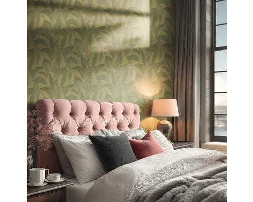 Útulná ložnice s tapetou se zeleným vzorem listů, růžovým čalouněným čelem postele a hřejivým osvětlením ze stolní lampy.