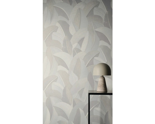 Vliesová tapeta s velkým vzorem listů za moderní stolní lampou na kovovém stolku.