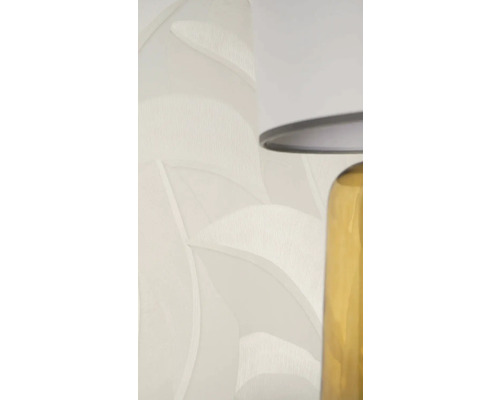 Vliesová tapeta se vzorem listů a texturou ve světle béžové barvě vedle stolní lampy.