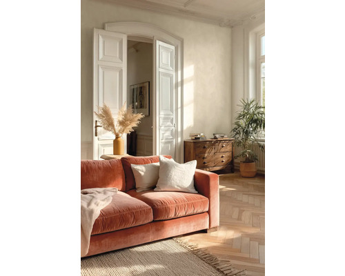 Světlý obývací pokoj se sametovou pohovkou v barvě terakoty, dřevěnými parketami, bílými křídlovými dveřmi a komodou z masivu.