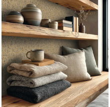 Rustikální dřevěná police a stěna s texturovanou tapetou, dekorativními vázami, polštáři a naskládanými dekami v útulném prostoru.