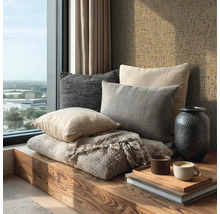 Dřevěná lavice u okna s dekoračními polštáři, strukturovanou dekou, tmavou vázou a strukturovanou tapetou.