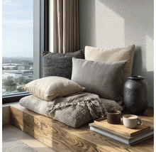 Útulné posezení na dřevěné lavici u okna s polštáři, tkanou dekou, vázou a šálky kávy na podnosu.