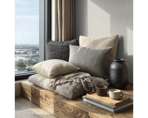 Útulné posezení na dřevěné lavici u okna s polštáři, tkanou dekou, vázou a šálky kávy na podnosu.