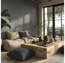 Světlý obývací pokoj se sedacími polštáři, dřevěným stolem a dekorací na strukturované stěně