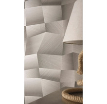 Tapeta s geometrickým vzorem, 3D efektem a jemnou liniovou strukturou ve světlé místnosti vedle lampy.