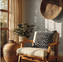 Dekorativní interiér s židlí, polštářem s geometrickým vzorem, velkou vázou a pokojovou rostlinou.