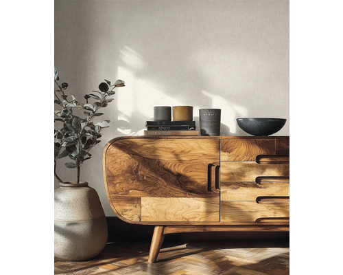 Světlý obývací pokoj s moderní dřevěnou komodou se zaoblenými rohy a výraznou kresbou dřeva před strukturovanou tapetou.