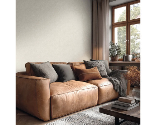 Světle hnědá kožená pohovka ve světlém obývacím pokoji s oknem a jemně strukturovanou světlou stěnou.