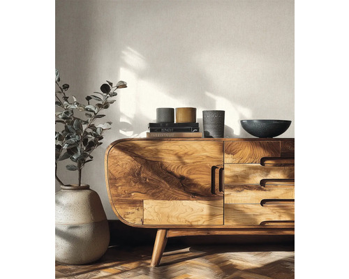 Světlý obývací pokoj s komodou z masivního dřeva, velkou podlahovou vázou s rostlinou a strukturovanou tapetou.