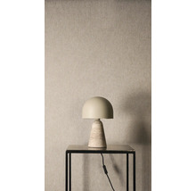 Stolní lampa s půlkruhovým stínidlem a kuželovou kamennou základnou na černém stolku před strukturovanou stěnou.