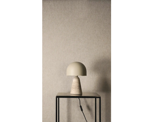 Stolní lampa s půlkruhovým stínidlem a kuželovou kamennou základnou na černém stolku před strukturovanou stěnou.