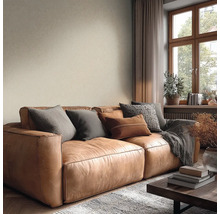 Útulný obývací pokoj s hnědou koženou pohovkou, polštáři, béžovou strukturovanou tapetou a dřevěným oknem.