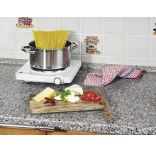 Scéna kuchyně s varnou deskou, těstovinami, sýrem a rajčaty na pracovní desce.