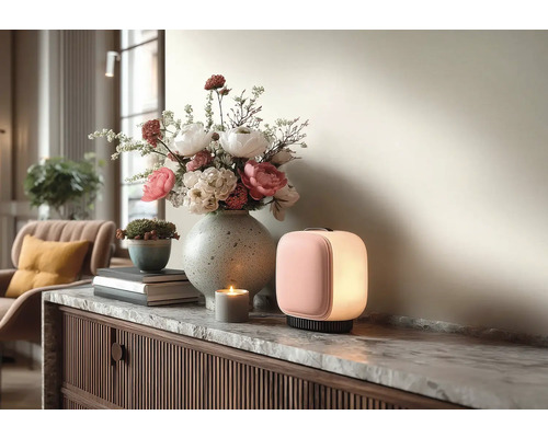 Moderní přenosná LED lampa, kamenná váza s květinami a svíčka na komodě s mramorovou deskou ve světlém interiéru.