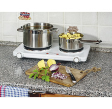 Dvojitá varná deska se dvěma nerezovými hrnci a ingrediencemi na krájecí desce