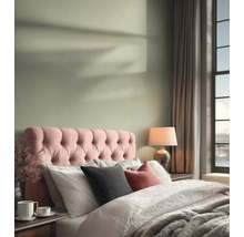 Světlá ložnice s růžovým prošívaným čelem postele, světle zelenou barvou stěny, útulným povlečením a stolní lampou.