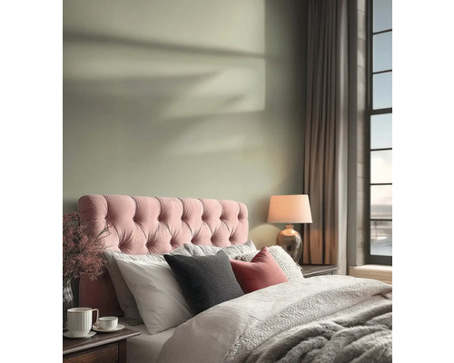 Světlá ložnice s růžovým prošívaným čelem postele, světle zelenou barvou stěny, útulným povlečením a stolní lampou.