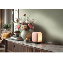 Moderní scéna obývacího pokoje s rozsvícenou přenosnou stolní lampou a velkou vázou s květinami na komodě s mramorovou deskou.