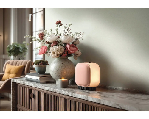 Moderní přenosná stolní lampa s růžovou přední částí a bílým světlem na mramorové komodě vedle vázy s květinami a svíčky.