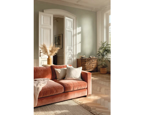 Světlý obývací pokoj se světle zelenou stěnou, rezavou sametovou pohovkou, parketami, jutovým kobercem a bílými křídlovými dveřmi.