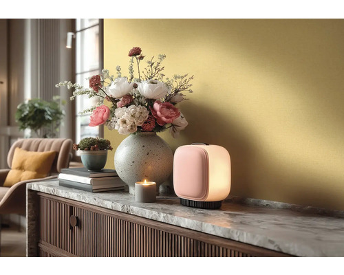 Moderní stolní lampa na komodě s mramorovou deskou, vedle váza s květinami, malý květináč a zapálená svíčka.