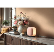 Dekorativní interiér se stolní lampou, květinovou vazbou a svíčkou na komodě.