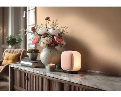 Dekorativní interiér se stolní lampou, květinovou vazbou a svíčkou na komodě.