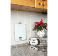 Bílá digitální kuchyňská váha na obkládané kuchyňské zdi