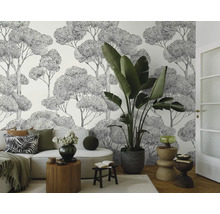 Světlá obývací místnost s pohovkou, pokojovou rostlinou a tapetou s motivem stromů