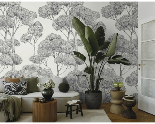 Světlá obývací místnost s pohovkou, pokojovou rostlinou a tapetou s motivem stromů
