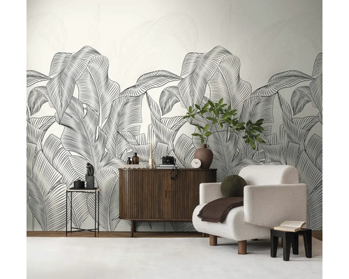 Obývací pokoj s velkoformátovou tapetou s motivem listů, křeslem a dřevěnou komodou