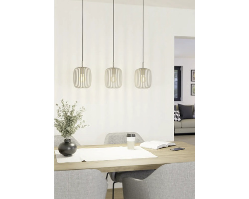 Tři kovová závěsná svítidla nad jídelním stolem s dekorací a židlemi.