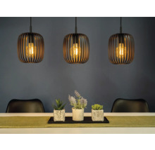 Scéna se třemi závěsnými svítidly nad stolem s dekorací a židlemi.