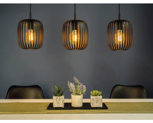 Scéna se třemi závěsnými svítidly nad stolem s dekorací a židlemi.