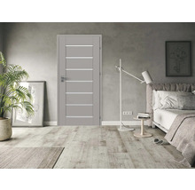 Moderní šedé interiérové dveře s vodorovnými skleněnými výplněmi ve světlé ložnici s dřevěnou podlahou a minimalistickým stylem.