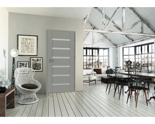 Moderní šedé interiérové dveře s horizontálními skleněnými výplněmi ve světlém pokoji s dřevěnou podlahou a přiznanými trámy.