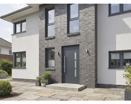 Moderní dům s šedými cihlami, vchodovými dveřmi a okny