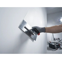 Ruka s hladítkem na sádru při hlazení stěny